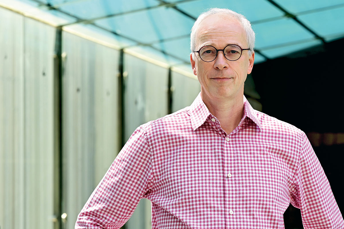 Thomas Tuschl wears a gingham button up shirt and looks into the camera for a portrait.