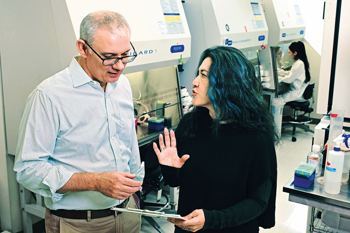 Paul Bieniasz and Theodora Hatziioannou converse in a lab.