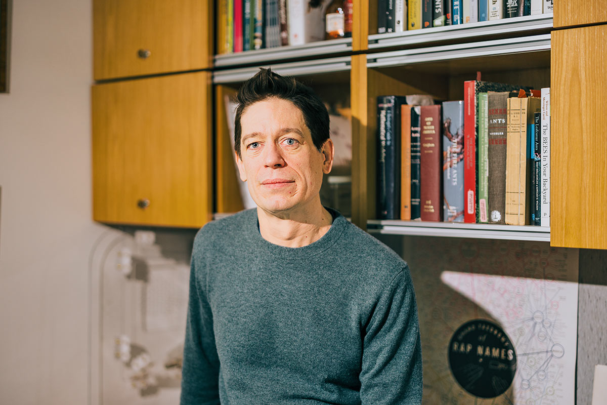 Kronauer leans against a desk in an office