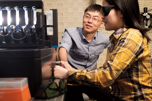 Liu (left) with postdoc Sai Li. The instrument they use to manipulate DNA is housed in a basement room with vibration-dampening walls. Photograph by Mario Morgado